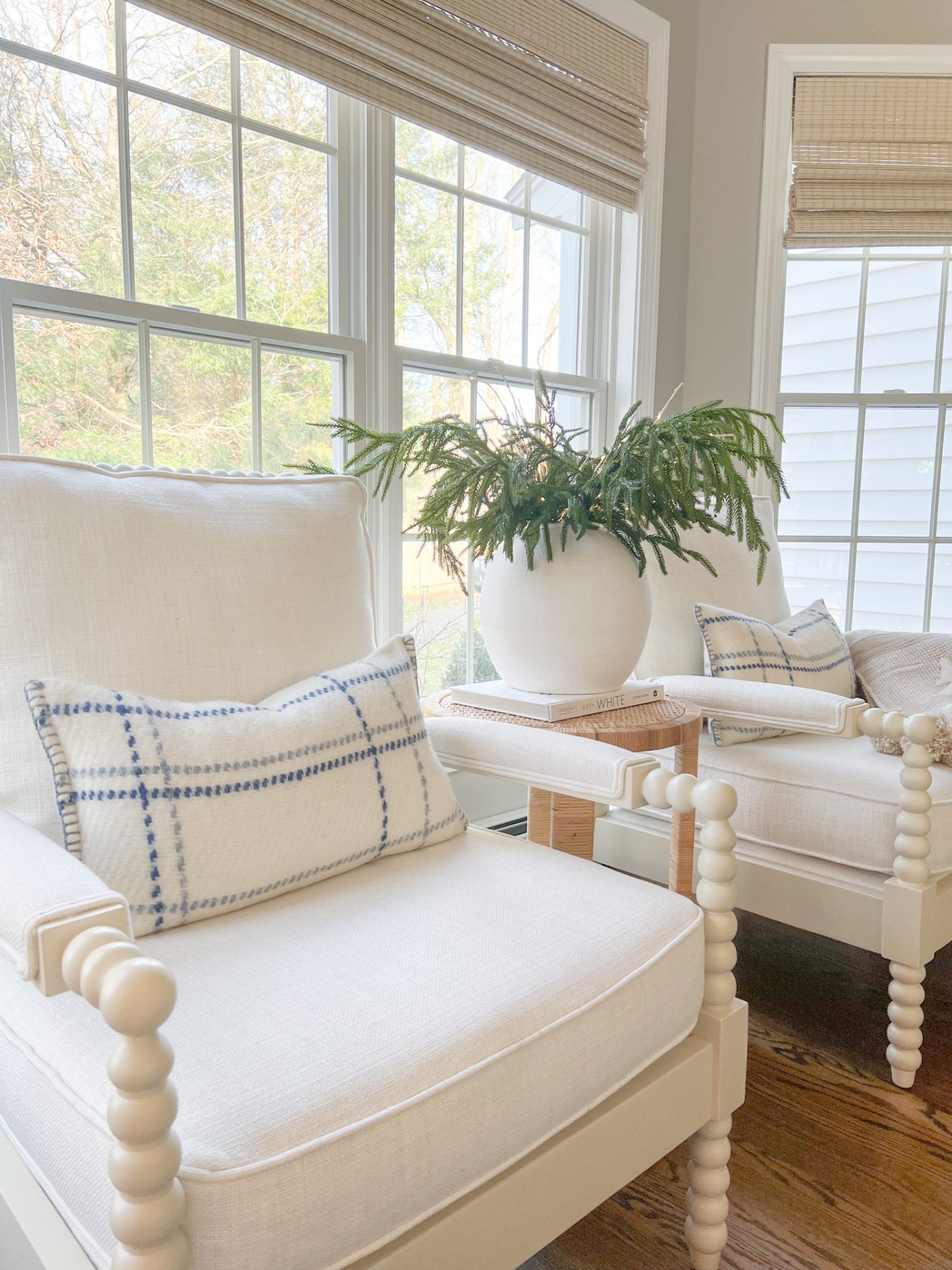 white armchair with Christmas pillows and Christmas greenery in a  white vase