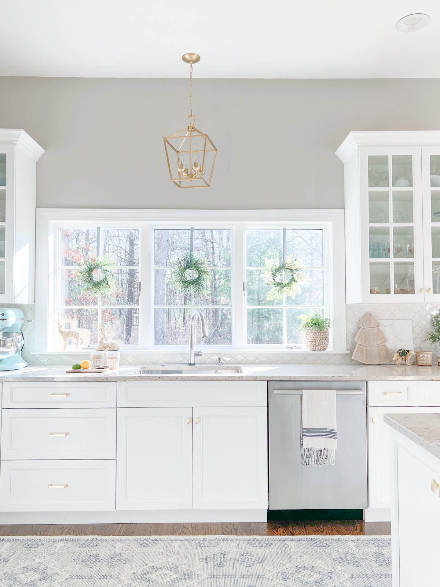 white kitchen cabinets with wreaths hanging on the windows