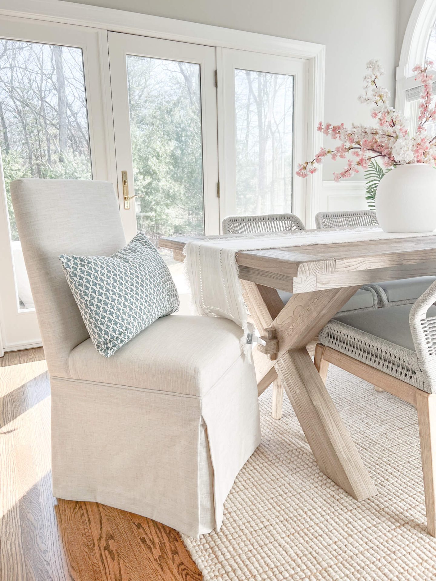 white upholstered chair at the head of a light wood dining table