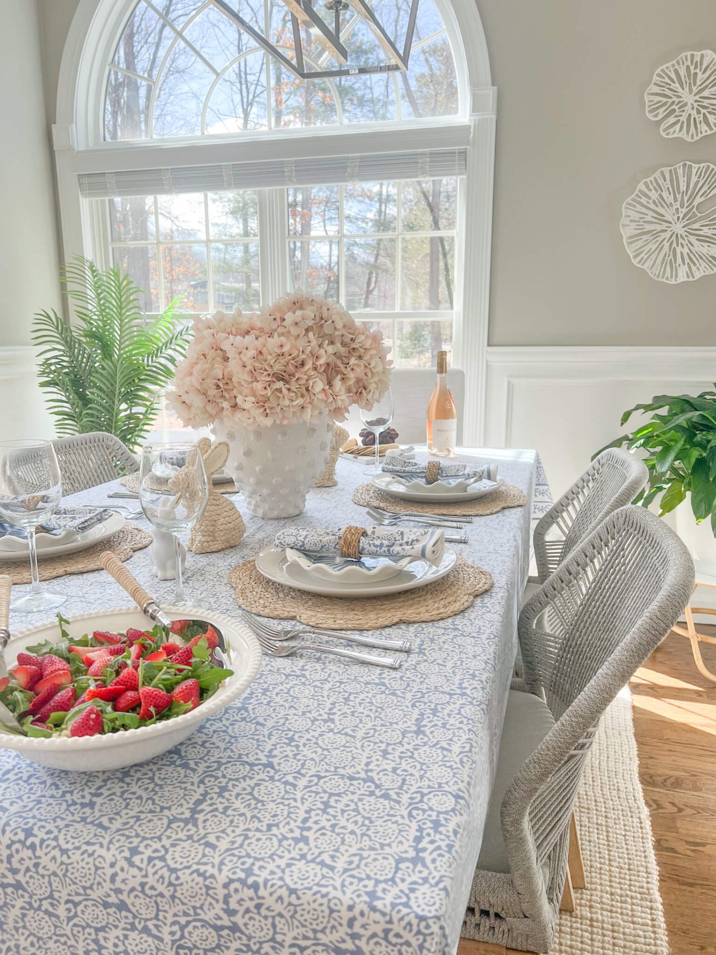bowl of strawberry salad with an easter tablescape with rattan placemat and easter bunny figurines