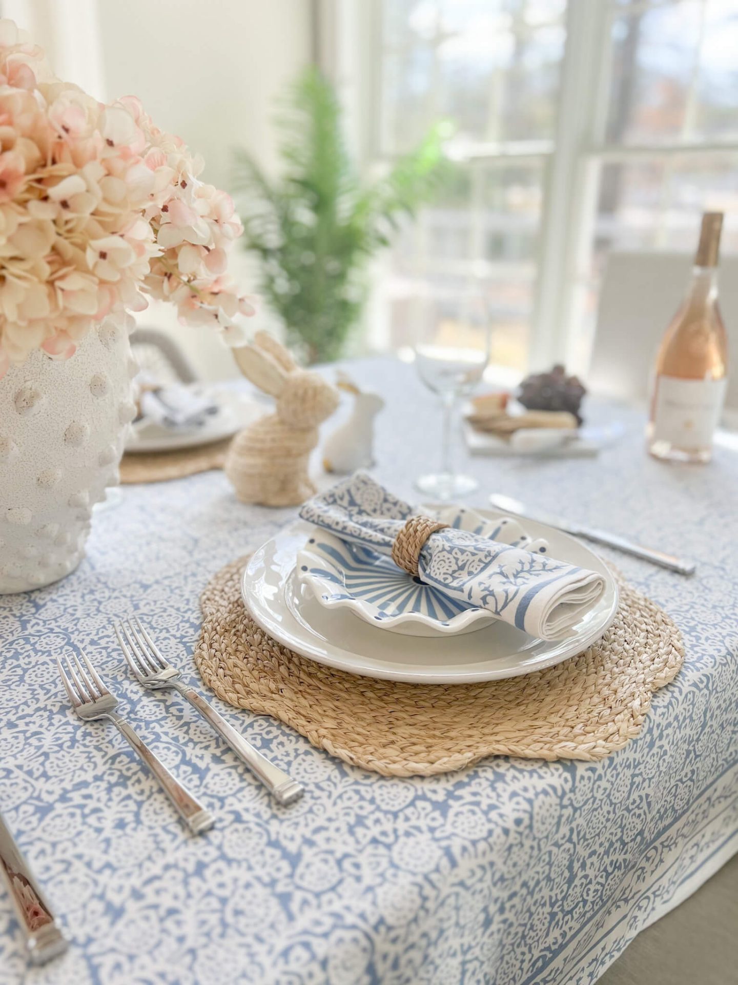 woven charger with rolled napkin and bottle of rose