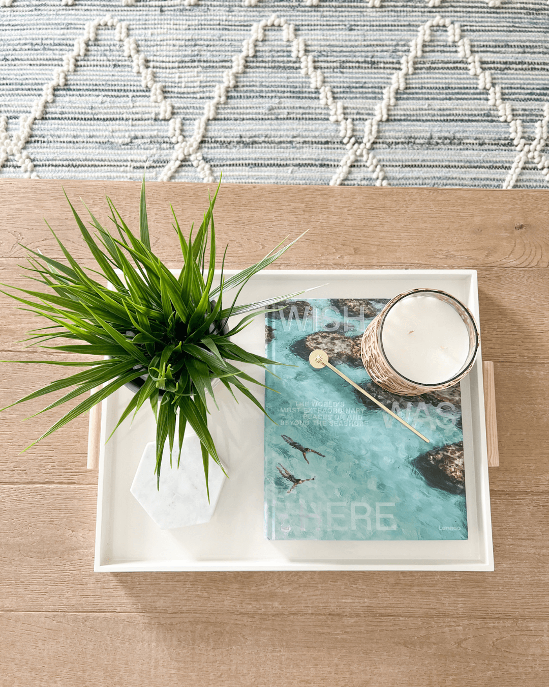 birds eye view of a coffee table with a tray, book, candle and greenery