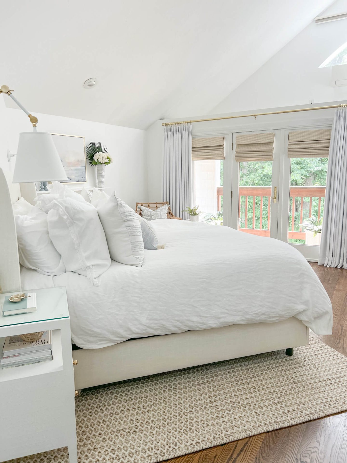 white bedroom with upholstered bed and curtains on large french doors