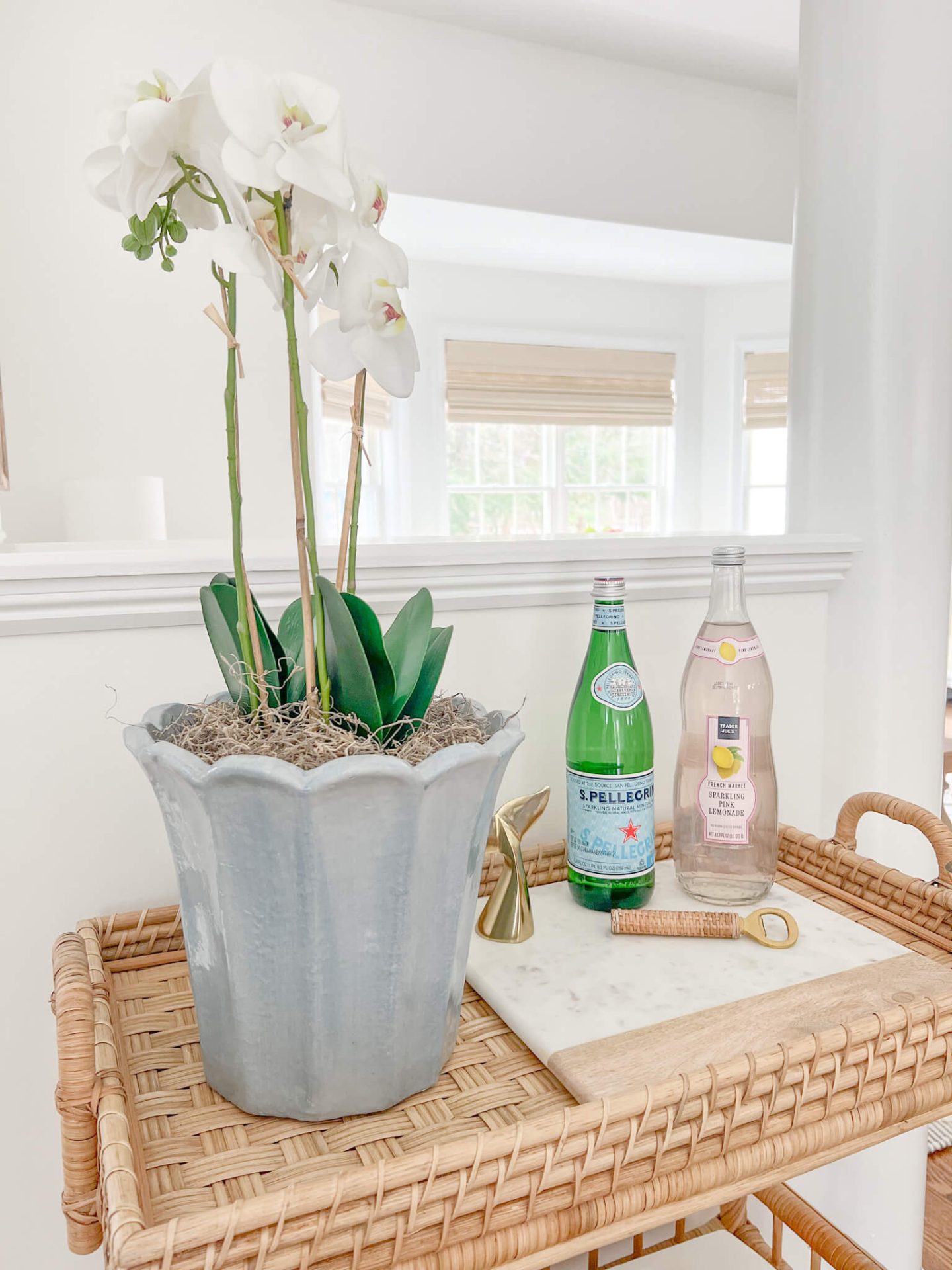 small orchid in a pot on rattan tray with sparkling water